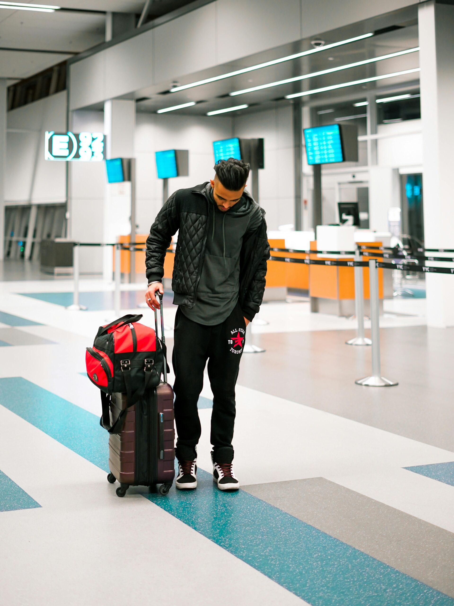 Man standing with luggage in a modern airport terminal, ready for travel.